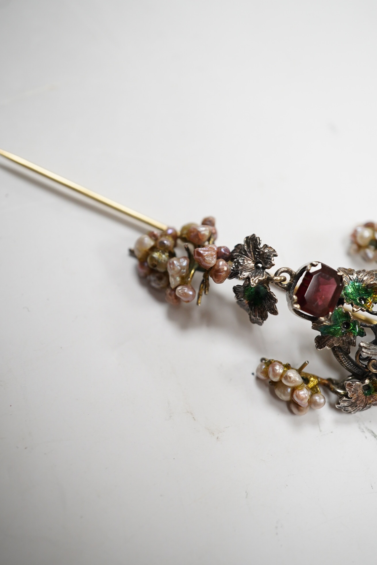 A 19th century Austro-Hungarian? gilt white metal, baroque pearl enamel and garnet set drop stick pin, decorated with birds and fruiting vines, 73mm. Condition - poor.